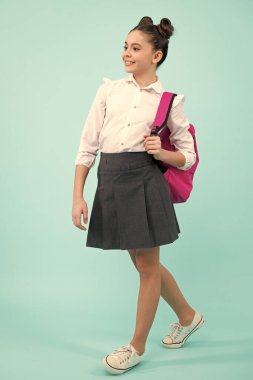 Schoolgirl in school uniform with school bag. Teenage girl student on blue isolated background. Learning knowledge and children education concept