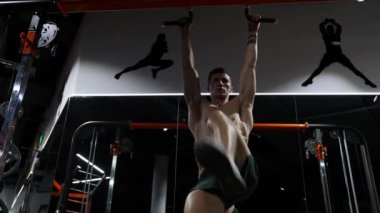 Karın kasları için egzersiz. Sportif adam karın kaslarını çalıştırıyor. Bacak kaldırarak altılı paket egzersizi. Spor salonunda kaslı vücutlu tişörtsüz bir sporcu. Kaslı sporcu karın kası egzersizi yapar. fitness.