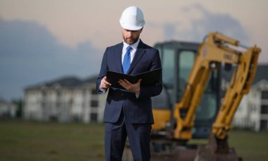 Kazıcının yanında inşaat işçisi. Evin önünde kendine güvenen bir inşaat sahibi. Mimar, inşaat mühendisi. İnşaat alanında güvenlik yeleği ve kasketi olan bir inşaat sahibi.