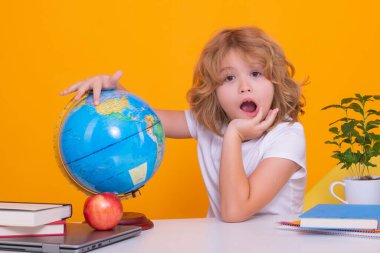 Okula dönelim. İlkokuldan elinde kitapla komik bir çocuk. Sarı stüdyo arka planında izole edilmiş okul çocuğunun portresi. Eğitim