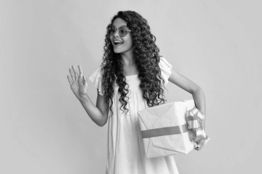 Mutlu ergen, pozitif ve gülümseyen çocuk duyguları. Sarı arka planda mevcut kutuya sahip ergen bir çocuk. Genç kız doğum günü hediyesi veriyor. Hediye, selam ve hediye konsepti