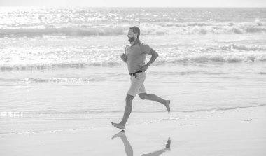 Koşucu özgürlüğü hisseder. Sabahın tadını çıkarıyorum. Dayanıklılık ve dayanıklılık. Neşeli sporcu sporcu okyanusta kazanmak için hızlı koşar. Sabah sporu aktivitesi. Sahilde koşan sağlıklı bir adam. enerjik yaz.