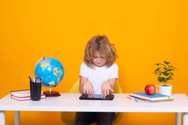 Kid boy from elementary school with book on yellow isolated background. Little student, smart nerd pupil ready to study. Concept of education and learning