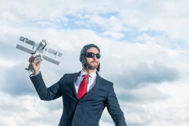 mature businessman in suit and pilot hat launch plane toy.