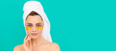 young woman has collagen golden eye patches on face with towel. Beautiful woman isolated face portrait, banner with mock up copy space