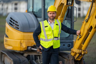 Takım elbiseli ve kasklı bir Buider. İnşaat yatırımcısı. İnşaat alanının önündeki yatırımcı. Başarılı bir yatırımcı. İnşaatta takım elbiseli yakışıklı ve kasklı bir adam.