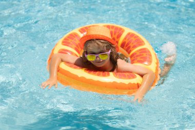 Mutlu çocuk, yaz tatilini dışarıda, yüzme havuzunda, suyun içinde keyifle geçiriyor.