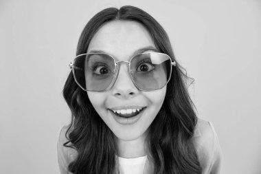 Yüzünde şok ifadesi olan genç bir kız çocuğu. Şaşırmış yüz ifadesi, sarı arka planda izole edilmiş. Mutlu sürpriz.