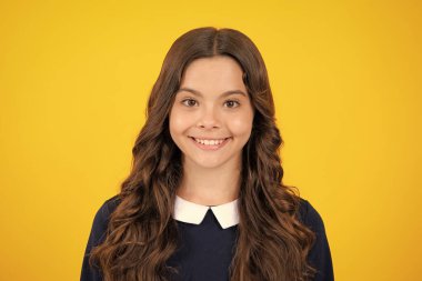 Portrait of beautiful happy smiling teenage girl on yellow studio background