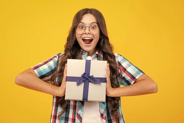 stock image Amazed teen girl. Child with gift present box on isolated studio background. Gifting for kids birthday. Excited expression, cheerful and glad