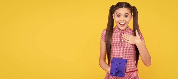 10代の贈り物だ 驚いた10代の女の子は黄色の背景にプレゼントボックスを保持 誕生日プレゼント付きの10代の女の子 水平方向のポスター コピースペース付きバナーヘッダー — ストック写真