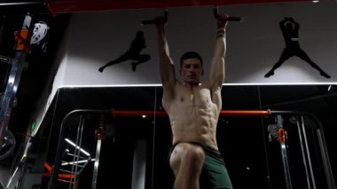 Spor salonunda kaslı vücutlu tişörtsüz bir sporcu. Kaslı sporcu karın kası egzersizi yapar. Karın kasları için egzersiz. Sportif adam karın kaslarını çalıştırıyor. Bacak kaldırarak altılı paket egzersizi. egzersiz.