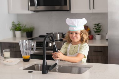 Aşçı çocuk ev mutfağında pasta yapmayı öğreniyor. Çocuk lezzetli yapıyor. Kurabiye ya da krep pişirmek için yumurta, süt ve un malzemesi.