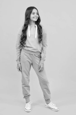 Stüdyo çocuklarının portresi. Mor spor takım elbiseli tatlı bir genç kız. Sarı arka planda şık bir takım elbiseli çocuk izole edilmiş.