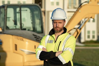 Worker with bulldozer on site construction. Man excavator worker. Construction driver worker with excavator on the background. Construction worker with tractor or construction vehicle at building