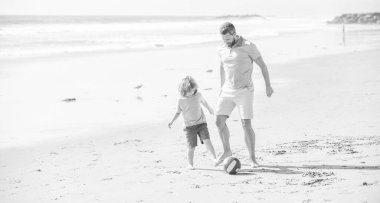 dad and child having fun outdoors. childhood and parenting. family holidays. sport activity. funny father and son play football on beach. daddy with kid boy on summer day. weekend family day.