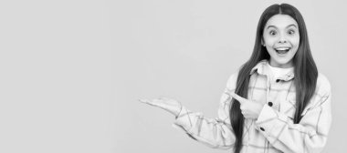 Şaşırmış çocuk pembe kareli gömlek giyer ürün sunar, fotokopi alanı, reklam. Çocuk yüzü, yatay poster, izole edilmiş genç kız portresi, fotokopi alanı olan pankart