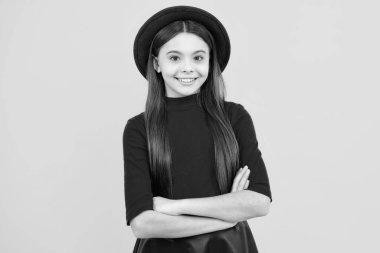 Mutlu ergen portresi. Kolları çapraz duran genç bir çocuğun portresi. Sarı arka planda fotokopi alanı var. Gülümseyen kız