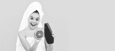 Çocuk yüz bakımı, kozmetoloji ve spa, sarı arka planda greyfurt şampuanı şişesi olan havluyla hayrete düşmüş genç bir çocuk. Fotokopi alanı olan güzel kız afişi