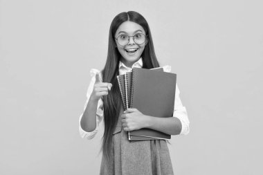 Back to school. Teenager schoolgirl with book ready to learn. School girl children on isolated yellow studio background. Excited face, cheerful emotions of teenager girl