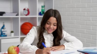 Neşeli çocuk deftere yazmaya, ders çalışmaya odaklanmış..