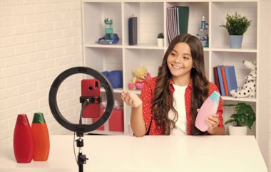 Genç çocuk akıllı telefonuyla sosyal medya için video dersi kaydediyor. Nüfuzlu genç, çevrimiçi yayınlanırken blog için yeni içerik oluşturuyor. Mutlu kız yüzü, pozitif ve gülümsüyor.