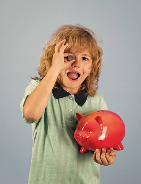 Saving money. Kid putting coin into piggy bank for saving with pile of coins. Piggybank with coins and child concept