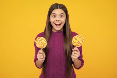 Teenage girl with candy lollipop, happy child 12, 13, 14 years old eating big sugar lollipop, sweets candy