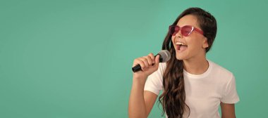 Karaoke 'de iyi eğlenceler. Karaoke çocuk şarkıcısı mavi arka plan. Mutlu çocuk mikrofona şarkı söylüyor. Müzik. Ayrı çocuk yüzünün yatay posteri, afiş başlığı, kopyalama alanı