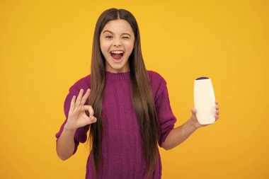 Heyecanlı bir yüz. Genç kız şişe şampuanı ya da duş jeli gösteriyor. Saç kozmetik ürünü. Reklam için şişe fotokopi alanı oluşturun. Şaşırtıcı bir ifade, neşeli ve mutlu.