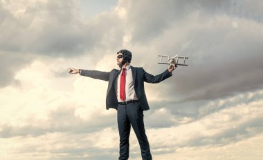 Takım elbiseli iş adamı ve pilot şapkalı uçak oyuncağı gökyüzünde. özgürlük.