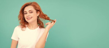 Mavi arka planda kıvırcık saçlı mutlu bir kızıl kız. İzole edilmiş yüz portresi, kopyalama alanı olan pankart