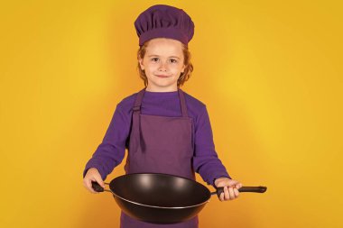 Çocuk aşçı aşçı aşçı. Üniformalı çocuk. Şef çocuk sarı arka planda izole edilmiş. Aşçı olmak için sevimli bir çocuk. Aşçı şapkası giymiş bir çocuk.