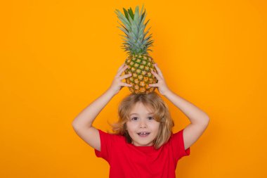 Summer fruits. Kid with pineapple in studio. Studio portrait of cute child hold pineapple isolated on yellow background