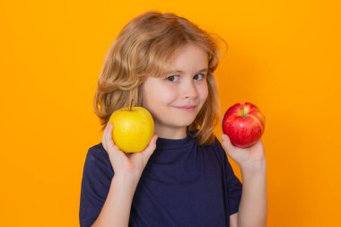 Healthy fruits for kids. Kid with apple in studio. Studio portrait of cute child hold apple isolated on yellow background