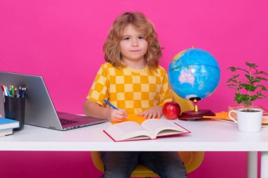 İlkokulda okuyan bir okul çocuğu. Pembe kırmızı izole edilmiş arka plan üzerine ders çalışan çocuk