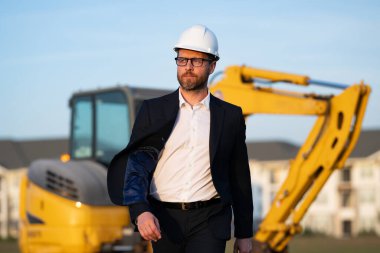 İnşaat mühendisi inşaat alanında çalışıyor. Evin arka planındaki mühendis. Modern ev inşaatında kendine güvenen mühendis. İspanyol inşaat mühendisi miğferinde