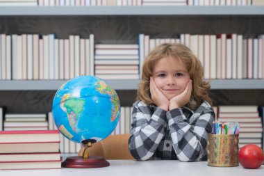 School kid looking at globe in library at the elementary school. Child from elementary school. Pupil go study. Clever schoolboy learning. Kids study, knowledge and education concept