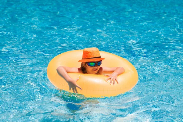 Child in swimming pool on inflatable ring. Little boy swim with orange float. Water toy for kids. Healthy outdoor sport activity for children. Kids beach fun