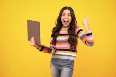 Amazed teenager. Teenager school girl hold notebook laptop. School children on isolated studio background. Excited teen schoolgirl