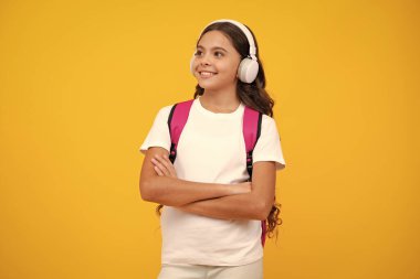 Liseli kız, kulaklıklı genç kız, sarı izole stüdyo geçmişiyle. Okul ve müzik eğitimi kavramı. Okula geri dön.