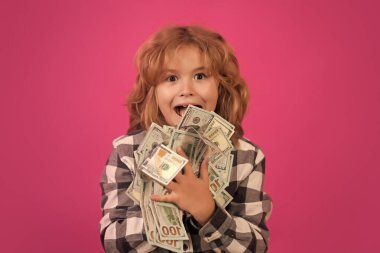 Kid having a lot of hundred dollars isolated on pink red background