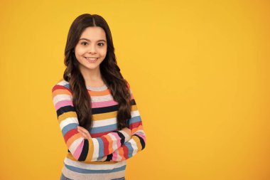 Sarı arka planda kollarını kavuşturan tatlı bir genç kız. Uzayı kopyala Mutlu ergen, pozitif ve gülümseyen genç kız duyguları