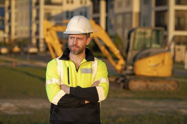 İnşaat alanında çalışan bir işçi. Şapkalı bir inşaatçı. Kasklı bir inşaat işçisi. Miğferli inşaat işçisi. İnşaat binasında sanayi işçisi. İnşaatçı, kazıcıyla birlikte inşaat alanında.