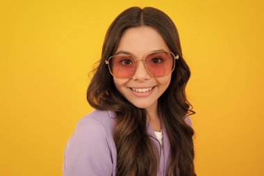 Teenager child with poor eyesight wear sunglasses, looking squinting. Kids glasses. Funny surprised adorable girl in round glasses having astonished shocked facial expression