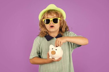 Saving money and piggy bank concept. Boy saving money in a piggybank. Child boy with american dollars money