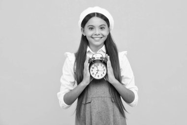 Punctual teen girl checking time. Child with alarm clock showing time. Happy girl face, positive and smiling emotions