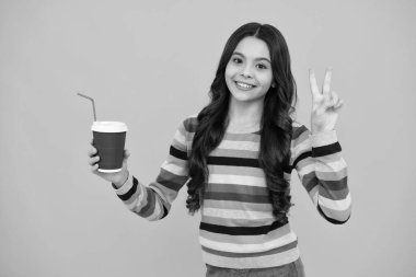 Genç kız elinde bir fincan sıcak kahve ya da çay tutuyor. Sarı arka planda paket bardağı olan çocuk, sabah enerji içeceği içeceği. Mutlu ergen, pozitif ve gülümseyen genç kız duyguları