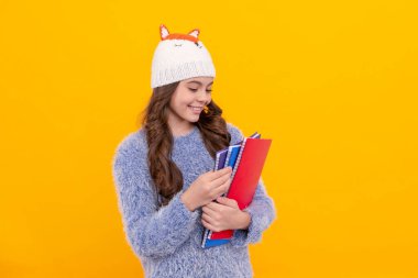 Uzun saçlı mutlu çocuk sarı arka plan, ödev defterini tutuyor..