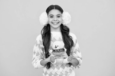 Sevgililer günü için sevgi dolu bir kalbi olan oyuncak ayıcığı olan çocuk. Günlük kıyafetli genç kız sarı arka planda doğum günü için yumuşak oyuncaklar tutuyor. Çocuk oyuncaklarıyla vakit geçiriyor.